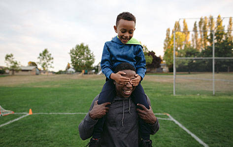 Man And Child Enjoying Shoulder Ride Together Outside In Field
